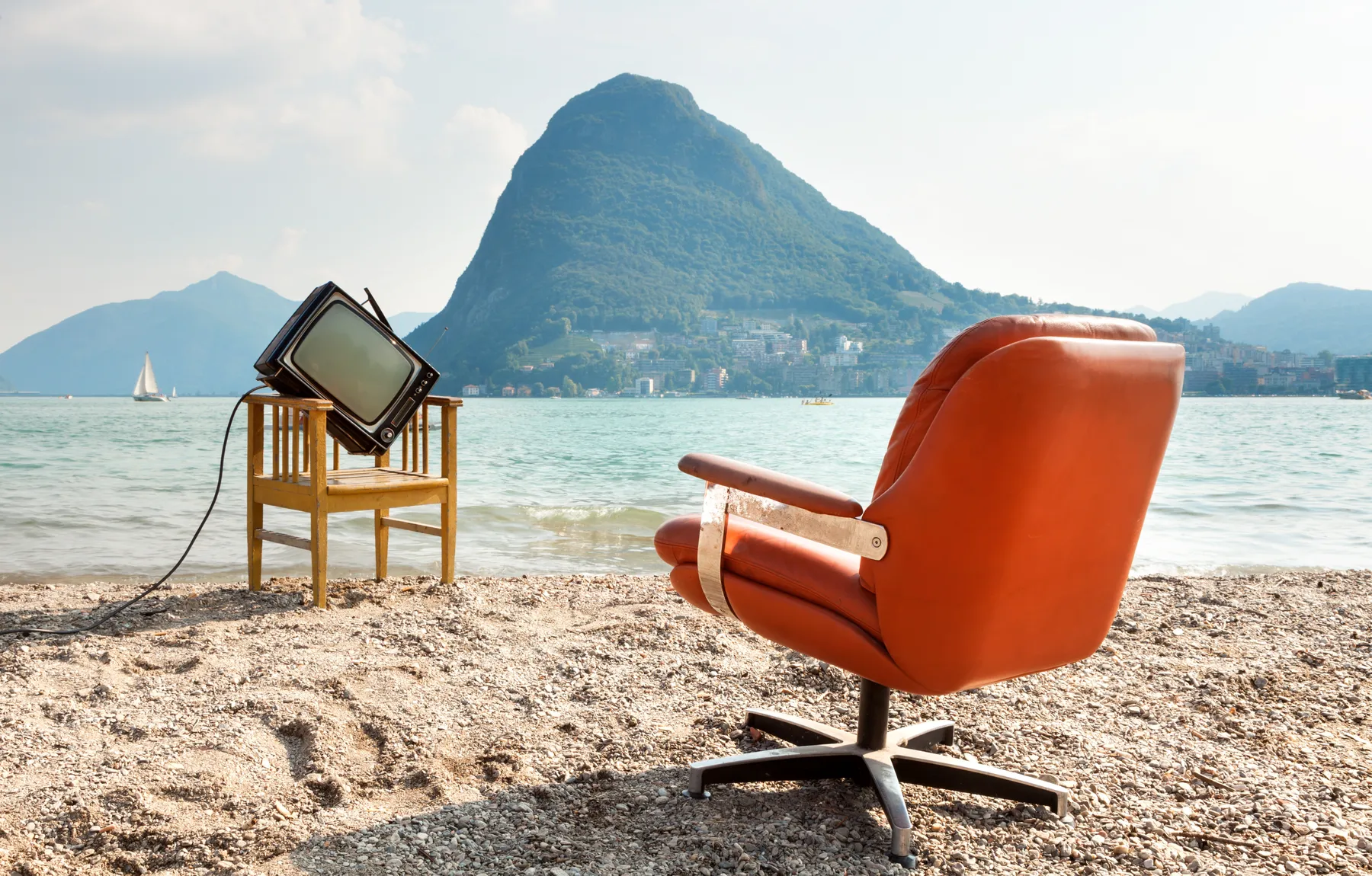 An office chair and television on a beach facing the lake